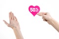 Valentine's Day discounts topic: Hand holding a card in the form of a pink heart with a discount of 50% on an isolated Royalty Free Stock Photo