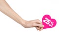 Valentine's Day discounts topic: Hand holding a card in the form of a pink heart with a discount of 25% on an isolated Royalty Free Stock Photo