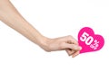 Valentine's Day discounts topic: Hand holding a card in the form of a pink heart with a discount of 50% on an isolated Royalty Free Stock Photo