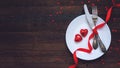 Valentine's Day Festive table setting, flat lay with two red heart shape chocolate candies on white plate, fork, knife and red Royalty Free Stock Photo