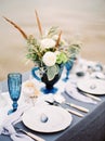 Valentine`s day. Fine art dinner on a beach. Blue wedding. Catering. Wedding bouquet with tender flowers in vase on table Royalty Free Stock Photo