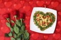 Valentine`s day food. Heart shaped pizza next to a red roses, on a red background, with bokeh of heart. Valentine`s day concept.