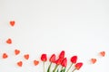 Valentine`s Day frame made of a bouquet of red tulips, hearts on a white background with a copy space