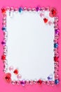 Valentine`s day frame on pink background made of pebbles in the shape of a heart with white space and paper hearts. Royalty Free Stock Photo