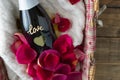 Valentine`s Day. Gift basket with champagne bottle with LOVE inscription. Decoration with red rose petals. Copy space