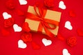 Valentine\'s Day. Gift box of kraft paper with a red ribbon. Red background with hearts and roses around Royalty Free Stock Photo