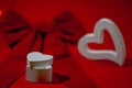 valentine's day gift in a white heart-shaped box on a background of a large red velvet bow on a red background with Royalty Free Stock Photo