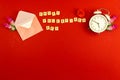 Valentine\'s day greeting card concept, red background, envelop and morning alarm clock, flowers, love theme, word on cubes