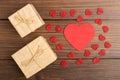 Valentine's Day greetings concept. Little red wooden crafted hearts and gift boxes on the wooden background.