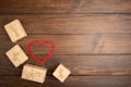 Valentine's Day greetings concept. Little red wooden crafted hearts and gift boxes on the wooden background.