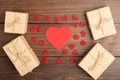 Valentine's Day greetings concept. Little red wooden crafted hearts and gift boxes on the wooden background.