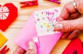 Valentine`s day holiday. woman`s hand with origami heart. putting paper heart to a pink envelope Royalty Free Stock Photo