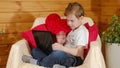 Valentine`s Day, kids. A cute little boy is working or chatting via video call, on a laptop gadget on Valentine`s Day. Congratulat