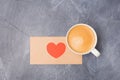 Valentine`s day love letter and coffee on grey desk. Craft envelop with red Red heart and coffee free space