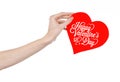 Valentine's Day and love theme: hand holds a greeting card in the form of a red heart with the words Happy Valentine's day