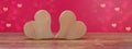 Valentine`s Day Love wedding banner greeting card template - two wood hearts on rustic wooden table and pink background texture Royalty Free Stock Photo