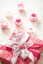 Valentina`s day and mothers day concept, red gift box with bow and roses on light wooden background