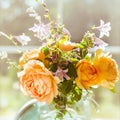 Valentine`s Day, orange English rose flowers in a glass jar on the background of a large window of a wooden house