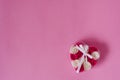 Rose flowers in a transparent box in the shape of a heart, tied with a white satin ribbon with a bow on a pink background Royalty Free Stock Photo