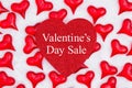 Valentine`s Day Sale message on glitter heart with red hearts on white fabric