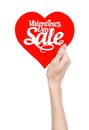 Valentine's Day and sale topic: Hand holding a card in the form of a red heart with the word Sale isolated on white background Royalty Free Stock Photo