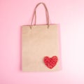 Valentine`s day, shopping and sale concept with paper bag and red wicker heart on it on pink backdrop