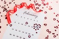 Valentine`s Day. Small red hearts highlight the date February 14 on a calendar sheet and a red ribbon on a pink heart-strewn Royalty Free Stock Photo