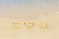 Valentine`s day on a sunny beach. Text I love you. Declaration of love in the sand, washed away by the sea wave. Love