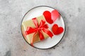 Valentine`s Day Table Setting. Plate with Gift box and two red hearts. Flat lay, top view Royalty Free Stock Photo