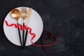 Valentine`s Day table setting with plate, gold knife, fork, spoon, red ribbon with heart Royalty Free Stock Photo