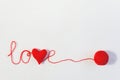 Valentine`s day or wedding backdrop. Red knitted volume heart in the word love and ball of thread on white knitted