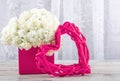 A bouquet of white roses in a pink box and a pink picture frame rattan heart, close-up. Royalty Free Stock Photo