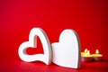 Valentine`s Day - White big hearts on the red background of the ass lit romantic candles . An atmosphere of love and warmth. Royalty Free Stock Photo