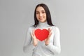 Valentine`s Day. Woman standing isolated on gray with heart card smiling cute Royalty Free Stock Photo