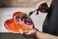 Valentine`s Day. Woman taking a slice of wild berry mouse cake from a heart shaped plate. Selective focus