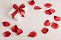 Valentine`s gift with red ribbon and red rose petals. Royalty Free Stock Photo