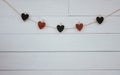 Valentine`s hearts hangin on natural cord Wooden white background. Retro style.