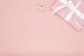 Valentine or women day pink gift with white bow ribbon decorated with small hearts on coral paper background. Flat lay.