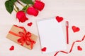 Valentine's Day background. A bouquet of red roses, a gift with a red ribbon, an empty notebook with a place for text . Royalty Free Stock Photo