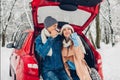 Valentine& x27;s day. Couple in love sitting in car trunk drinking hot tea in snowy winter park. People relaxing outdoors Royalty Free Stock Photo