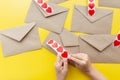 Valentine& x27;s day. Hands glue red hearts on envelopes, yellow background. The holiday is February 14. Love letters