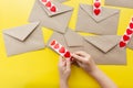Valentine's day. Hands glue red hearts on envelopes, yellow background. The holiday is February 14. Love letters