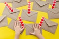 Valentine& x27;s day. Hands glue red hearts on envelopes, yellow background. The holiday is February 14. Love letters