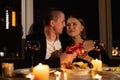 Valentine's day passionate couple having dinner by candlelight, night meeting man woman giving a gift, romantic date Royalty Free Stock Photo