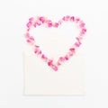 Valentines background. Heart symbol. Petals of roses and vintage paper cards on white background. Flat lay, Top view. Royalty Free Stock Photo