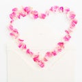 Valentines background. Heart symbol. Petals of roses and vintage paper cards on white background. Flat lay, Top view. Royalty Free Stock Photo