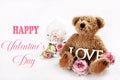 Valentines card with cute teddy bear with with roses and LOVE inscription sitting on white background with copy space