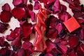 Red candle in the shape of loving couple intertwined and a jewelry gift box with rose petals on background Royalty Free Stock Photo