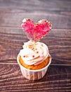 Valentines cupcake cream cheese frosting decorated with heart candy lollipop on the wooden background