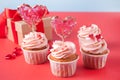 Valentines cupcakes cream cheese frosting decorated with heart candy lollipops and gift box on the background.